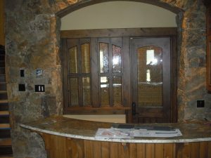 A kitchen with a stone counter top and a wooden door.