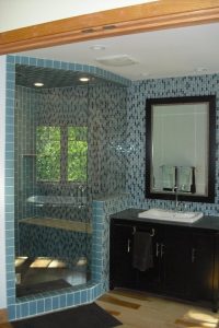 A bathroom with blue tile and a shower.