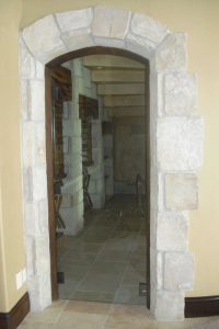 A stone archway leading to a home's entrance, framed by a wooden door.