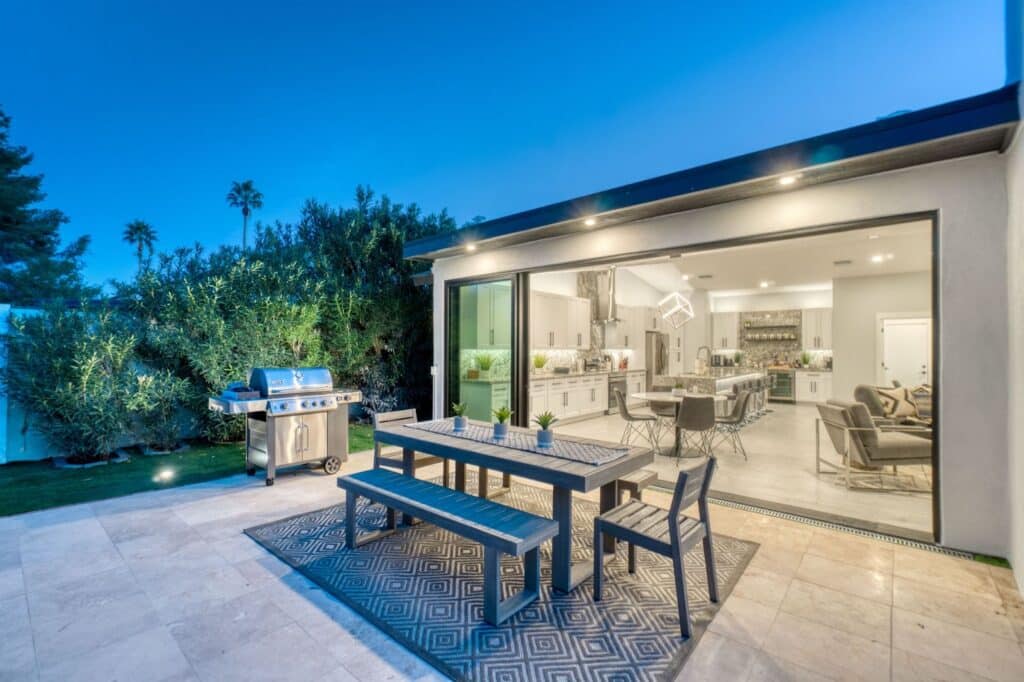 Grill and dining table on patio, with sliding glass doors leading to the indoors